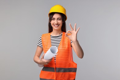 Photo of Architect in hard hat with draft showing ok gesture on light grey background