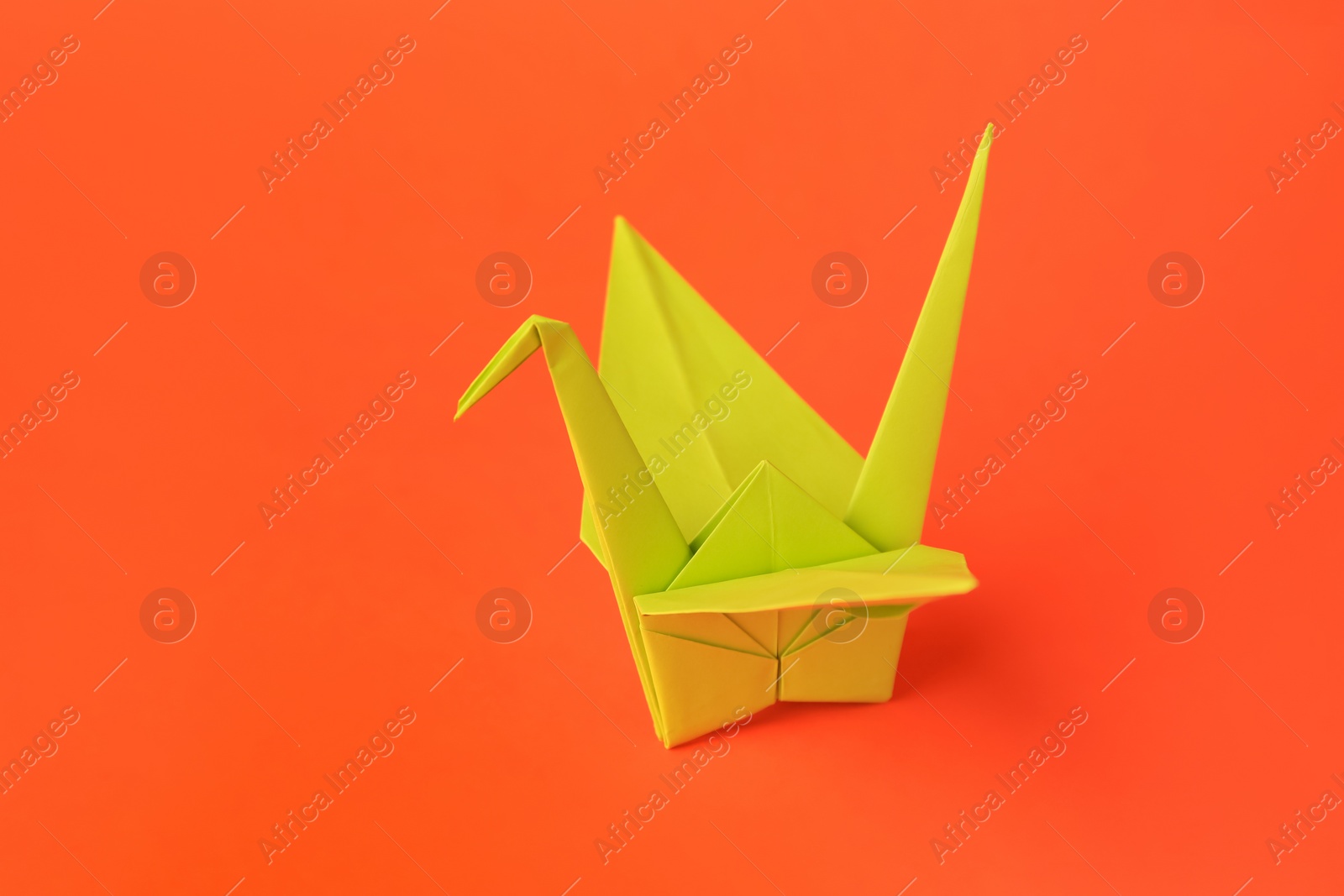 Photo of Origami art. Handmade paper crane on orange background