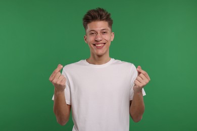 Photo of Happy man showing money gesture on green background