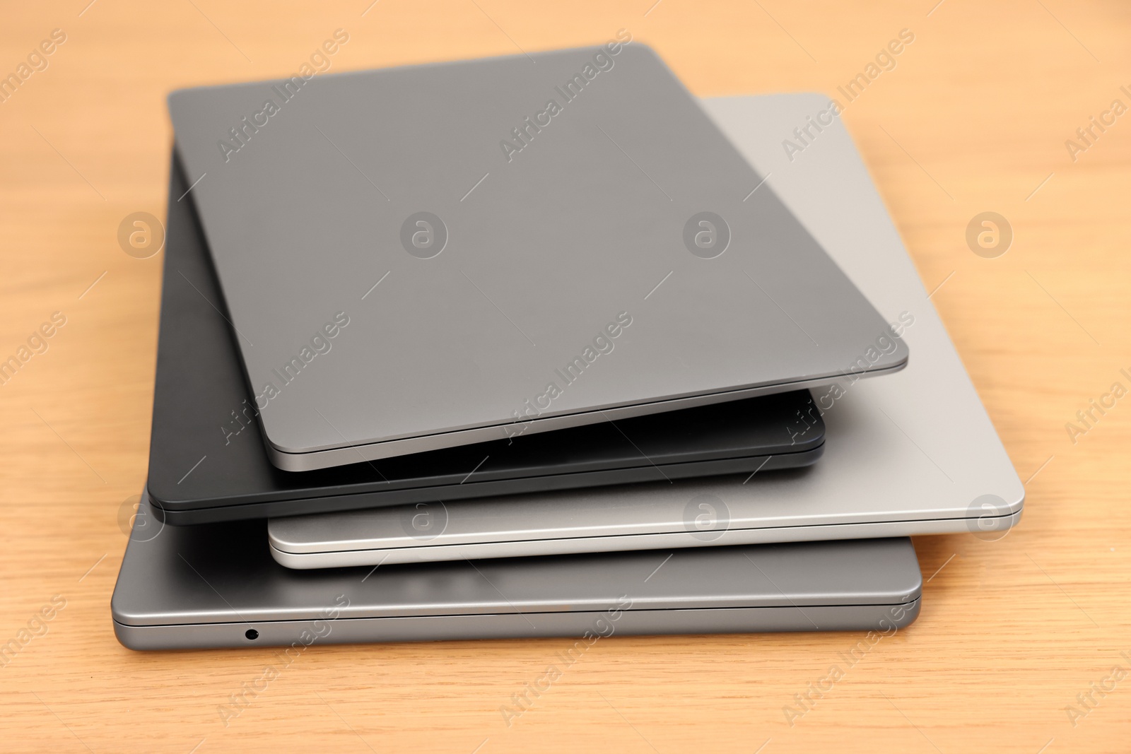 Photo of Different modern laptops on wooden table, closeup