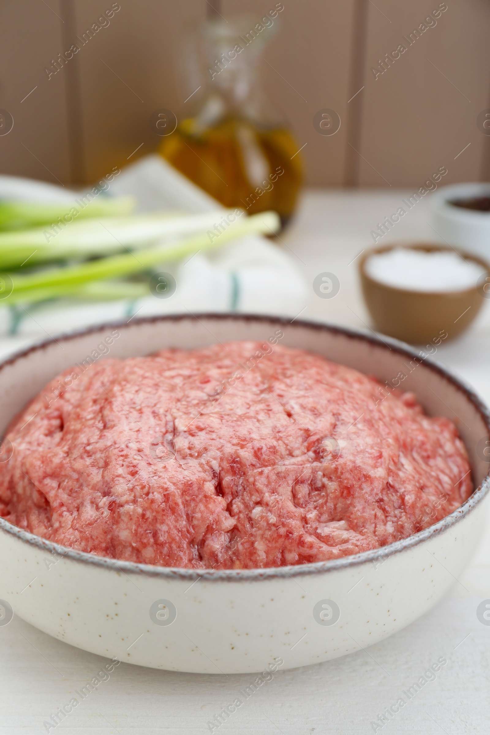 Photo of Bowl of raw fresh minced meat on white wooden table, closeup