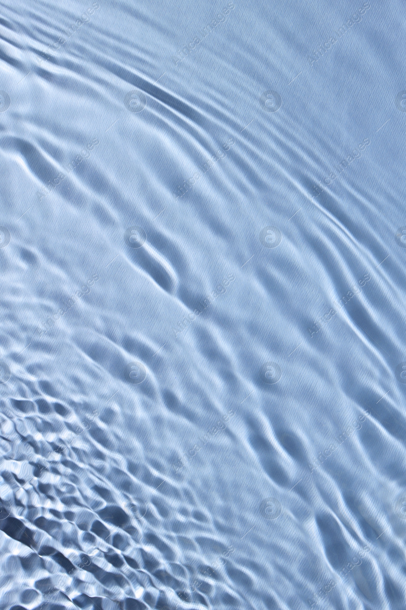 Image of Rippled surface of clear water on light blue background, top view