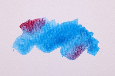 Photo of Blot of bright watercolor paints on white paper, top view