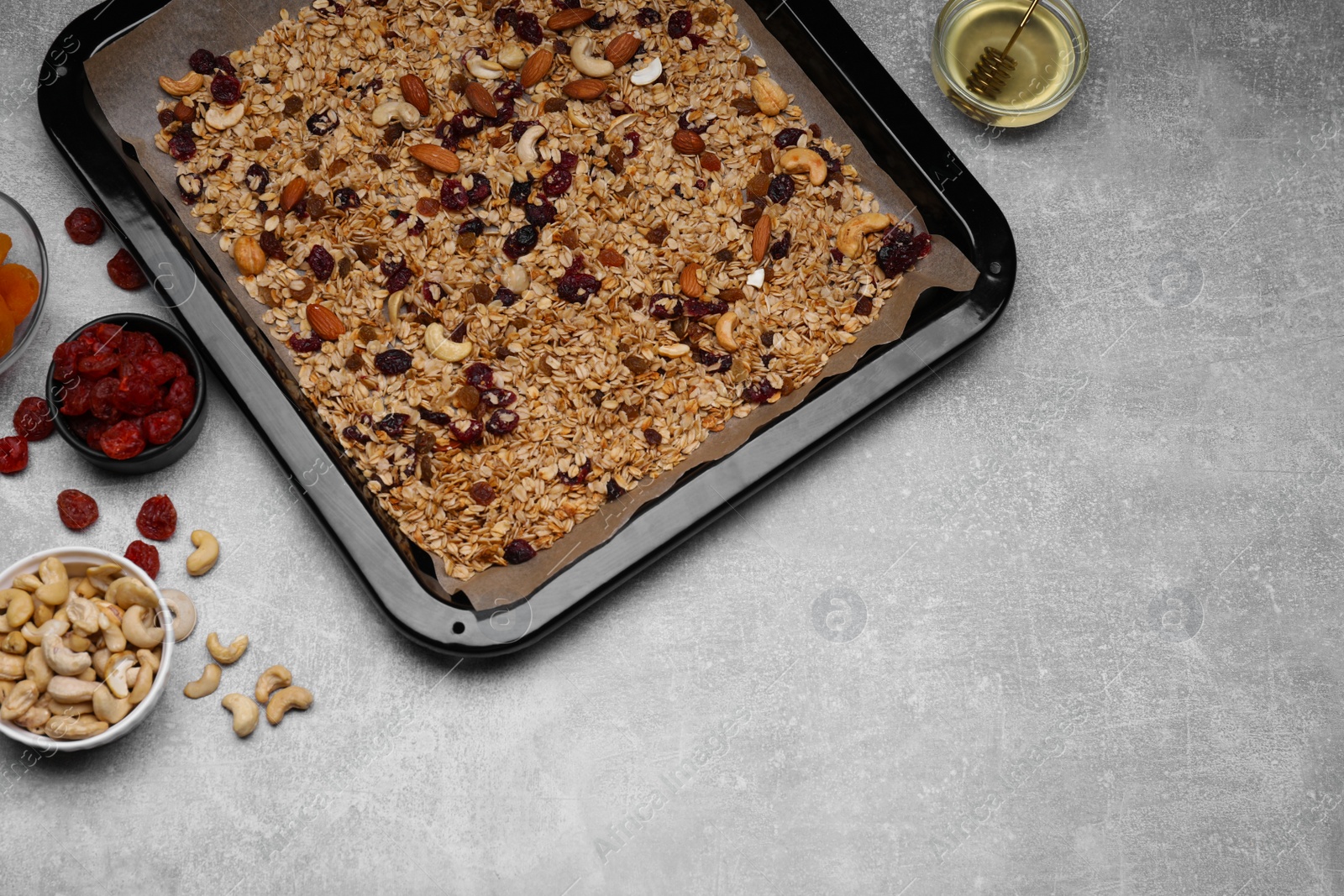 Photo of Tray with tasty granola, nuts and dry fruits on light grey table, flat lay. Space for text