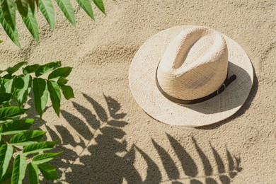 Photo of Stylish straw hat on sand outdoors, above view