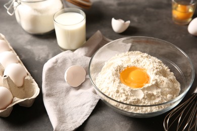 Making dough. Flour with egg yolk in bowl on grey textured table, closeup