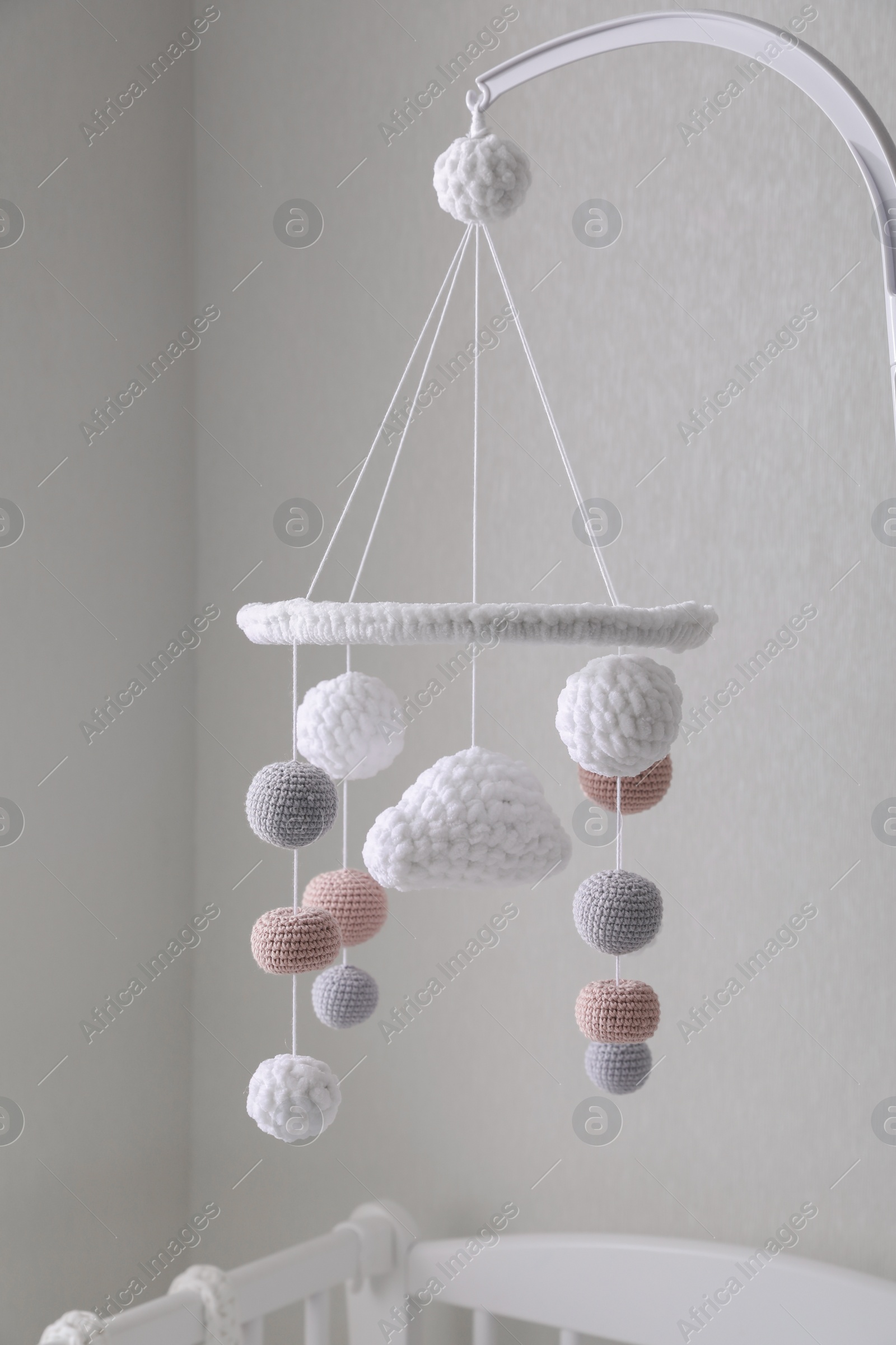 Photo of Modern baby crib mobile near beige wall in room