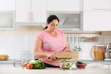 Woman preparing vegetable salad on table in kitchen. Healthy diet