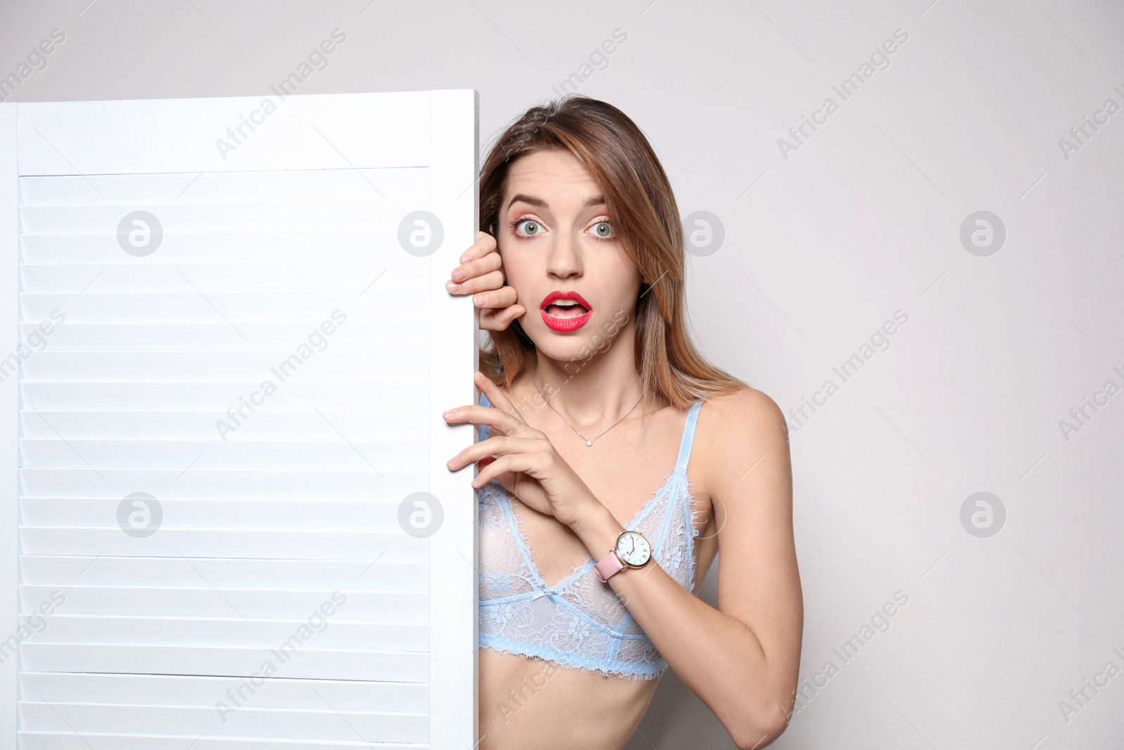 Photo of Young woman behind folding screen against light background, space for text. Dressing room