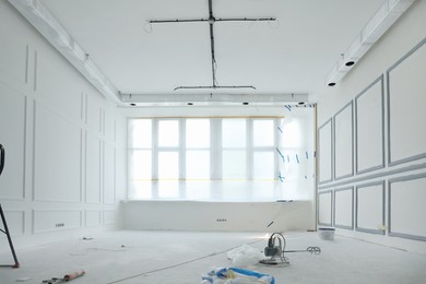 Window covered with plastic film and tools on floor in room