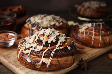 Delicious rolls with toppings and nuts on wooden table, closeup. Sweet buns