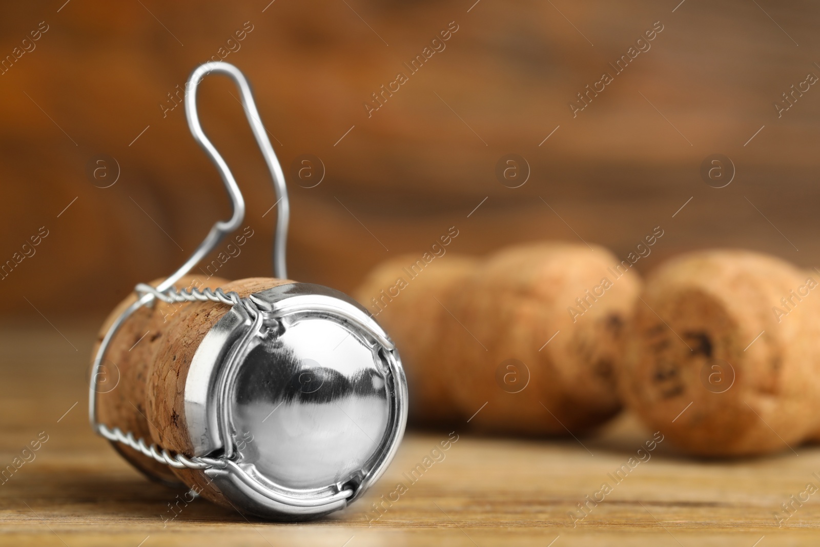 Photo of Sparkling wine cork with muselet cap on wooden table, closeup. Space for text