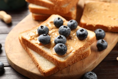 Photo of Delicious toasts with peanut butter and blueberries on table, closeup