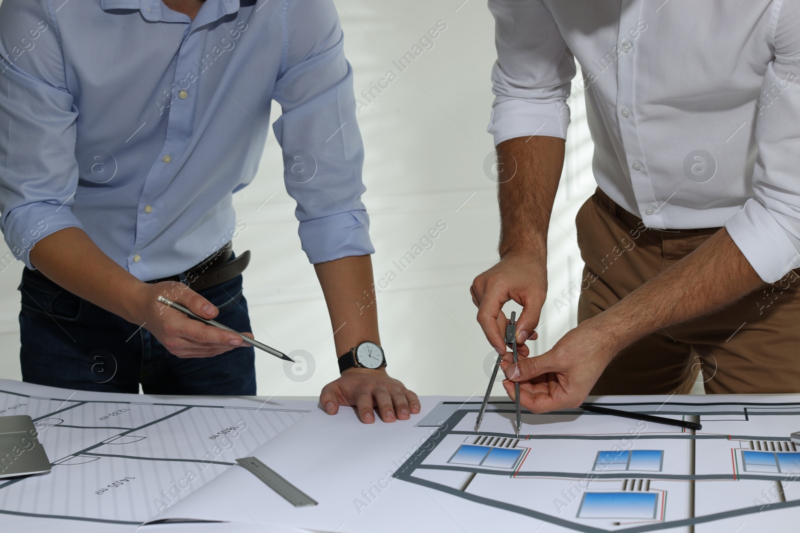 Photo of Architects working with construction drawings at table in office, closeup