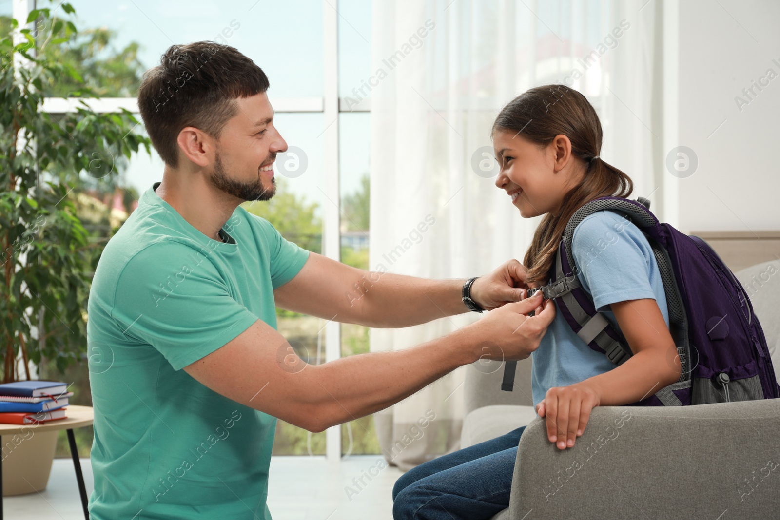 Photo of Father helping his daughter to get ready for school at home