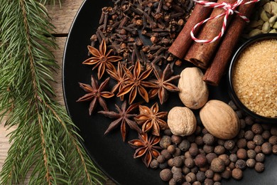 Photo of Dishware with different spices and fir branches on table, flat lay