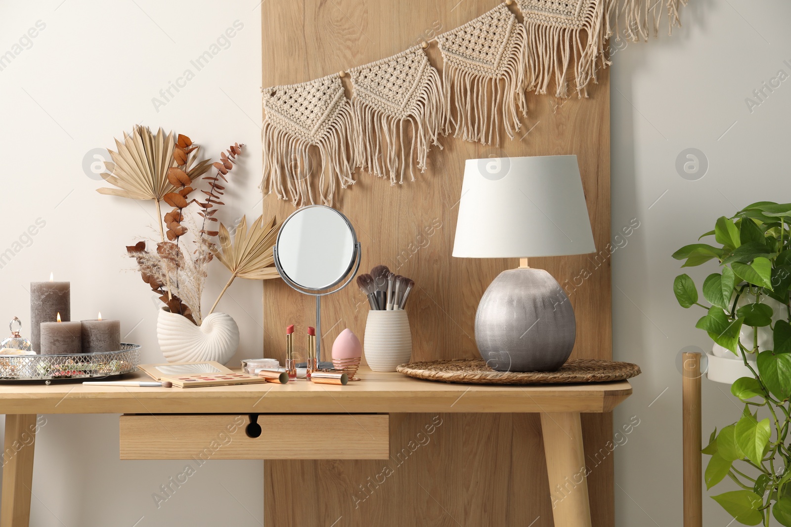 Photo of Dressing table with mirror, makeup products and decor in room