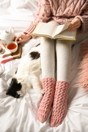 Woman reading book near adorable cat on bed, view from above