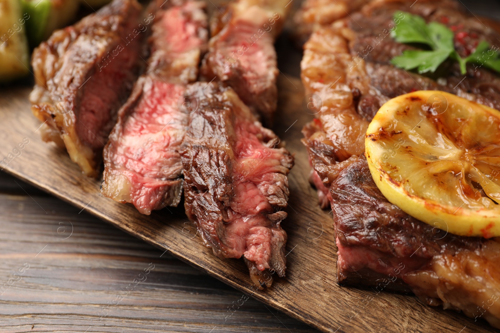 Photo of Delicious grilled beef steak on wooden table, closeup