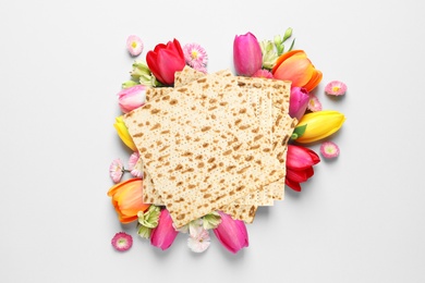 Image of Tasty matzos and flowers on light background, flat lay. Passover (Pesach) celebration