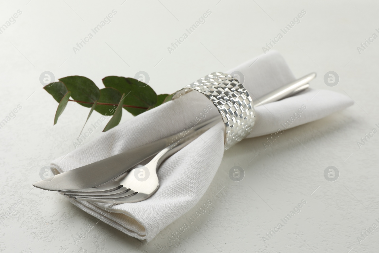 Photo of Stylish setting with cutlery and napkin on white textured table