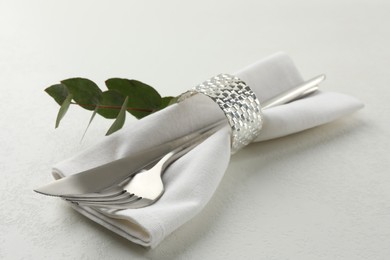 Stylish setting with cutlery and napkin on white textured table