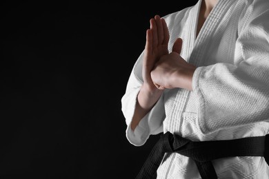 Photo of Man wearing keikogi and black belt on dark background, closeup with space for text. Martial arts uniform