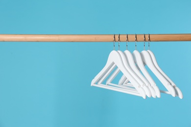 Wooden rack with clothes hangers on color background, space for text