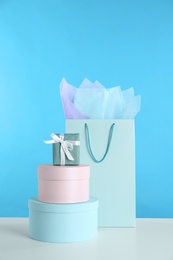 Photo of Gift bag and boxes on white table against light blue background