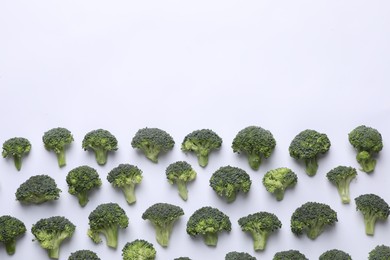 Many fresh green broccoli pieces on white background, flat lay. Space for text