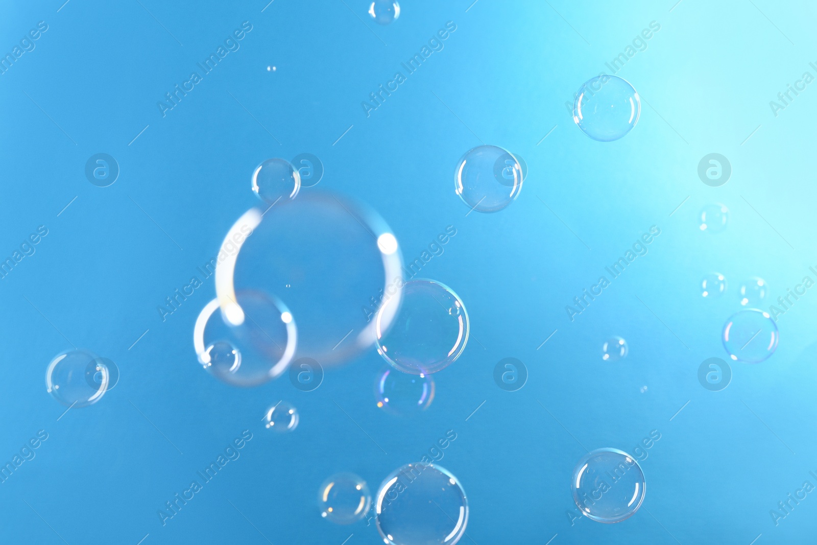 Photo of Beautiful transparent soap bubbles on light blue background