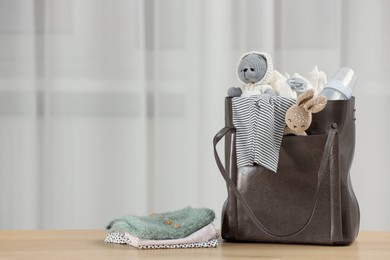 Photo of Mother's bag with baby's stuff on wooden table indoors. Space for text