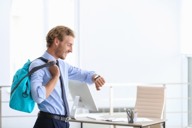 Photo of Young handsome businessman holding fitness bag in office. Space for text