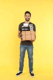 Young courier with different orders on color background. Food delivery service