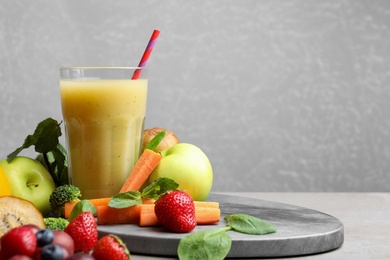 Photo of Delicious juice and fresh ingredients on grey table. Space for text