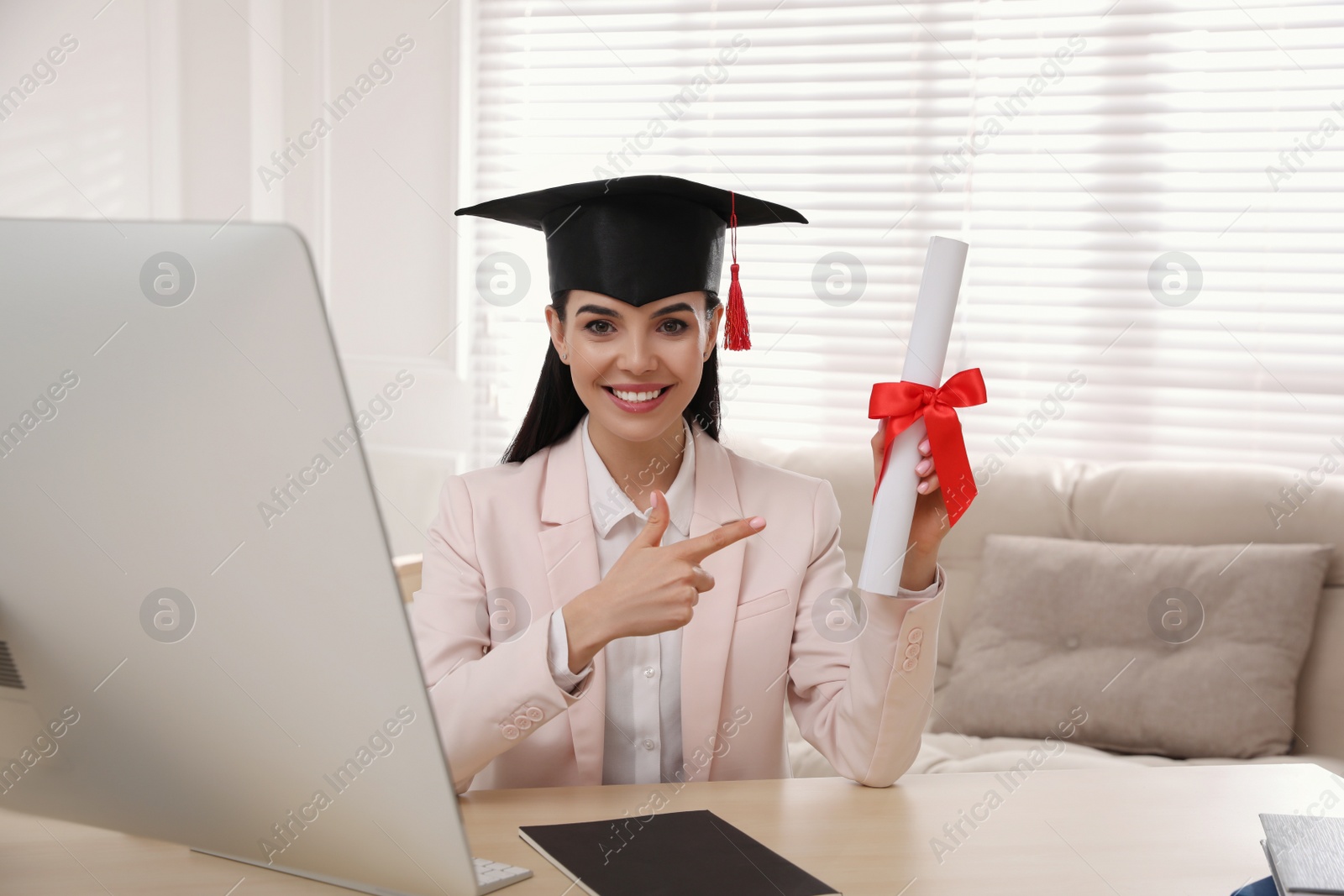 Photo of Happy student with graduation hat and diploma at workplace in office