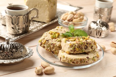 Photo of Tasty halva with pistachios and mint served on wooden table