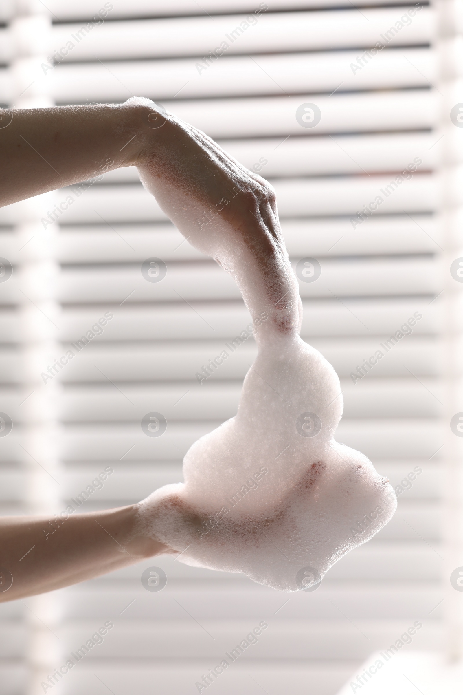 Photo of Woman washing hands with cleansing foam in bathroom, closeup