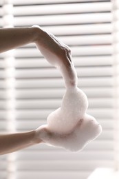 Woman washing hands with cleansing foam in bathroom, closeup