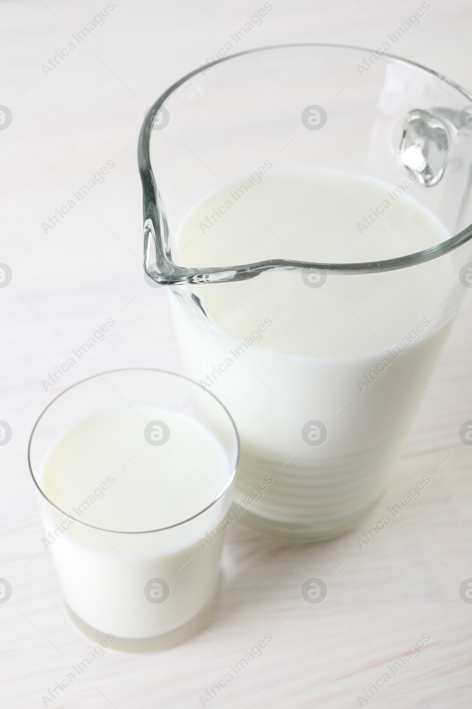 Photo of Jug and glass of fresh milk on wooden table