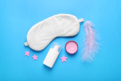 Photo of Flat lay composition with soft sleep mask, decorative stars and pink feather on light blue background