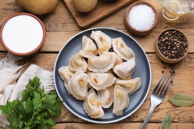 Delicious dumplings (varenyky) with potatoes and onion served on wooden table, flat lay