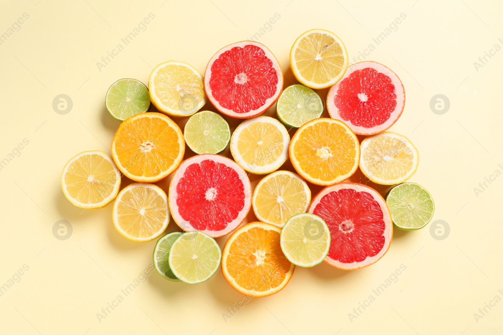 Photo of Different cut citrus fruits on beige table, flat lay