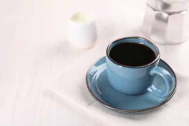 Photo of Delicious coffee in cup on white wooden table, closeup. Space for text