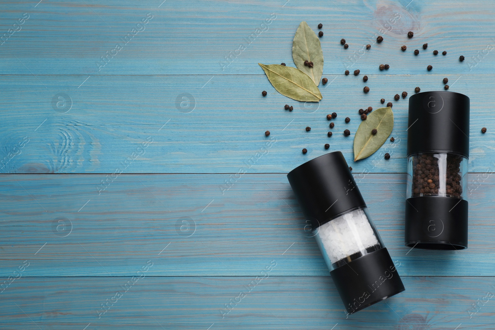 Photo of Salt and pepper shakers with bay leaves on turquoise wooden table, flat lay. Space for text