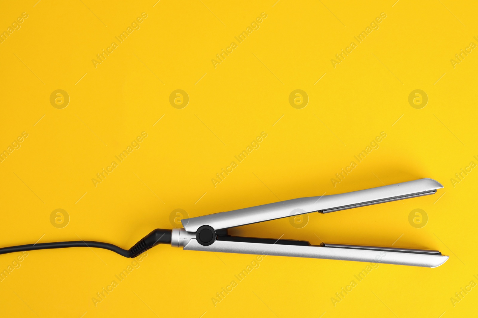 Photo of Modern hair iron for straightening on color background, top view with space for text