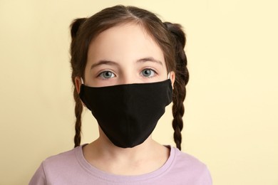 Photo of Girl wearing protective mask on beige background. Child's safety from virus