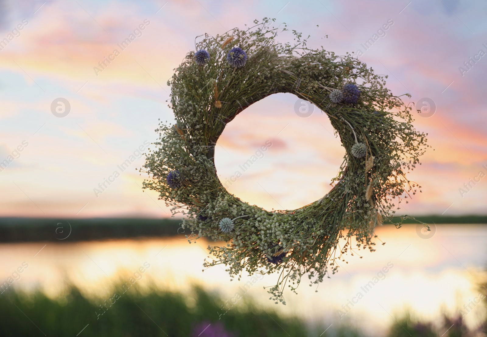 Photo of Wreath made of beautiful flowers hanging outdoors