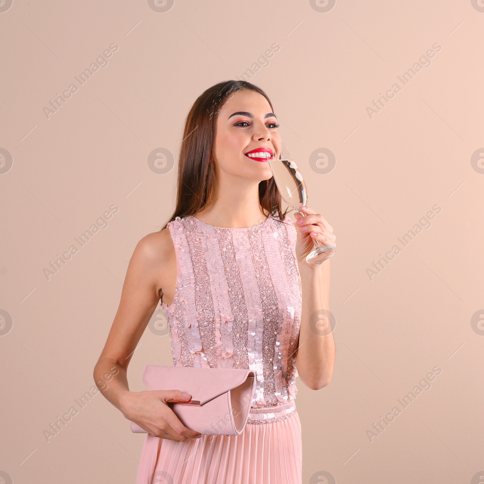 Photo of Portrait of happy woman with champagne in glass and handbag on color background