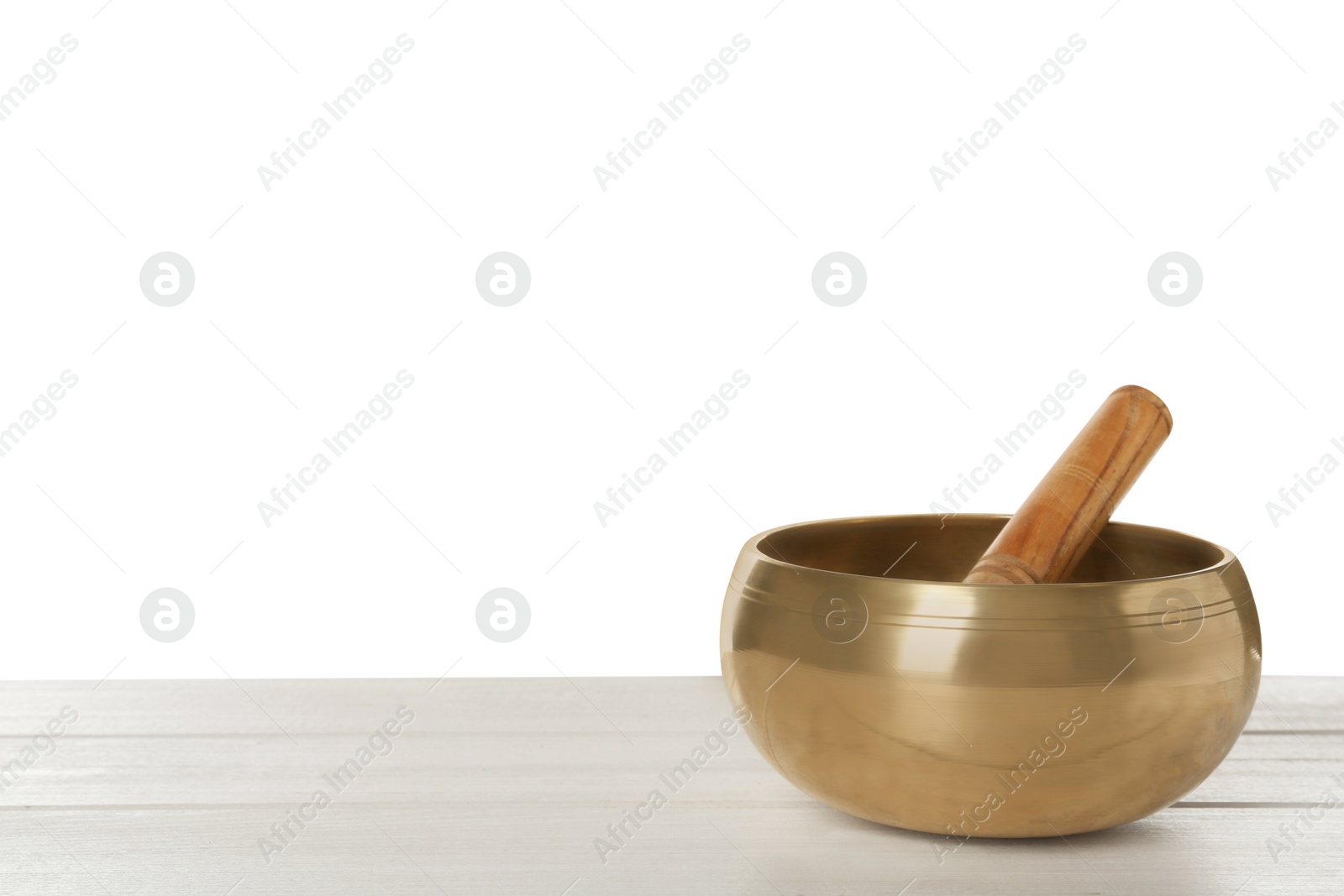 Photo of Golden singing bowl and mallet on wooden table against white background, space for text